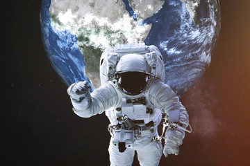 Fototapeta na wymiar Astronaut in a front of Earth planet of solar system with lens flare. Science fiction. Elements of the image were furnished by NASA