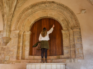 blonde woman visiting a touristic ancient church and pointing at some architectural detail os the...