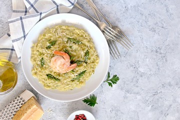 Italian risotto with spring asparagus and chrimps in plate on light background. Top view with copy space.