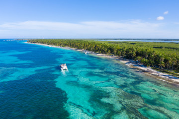 Aerial view from drone on tropical beach with palm trees and speed boats in caribbean sea