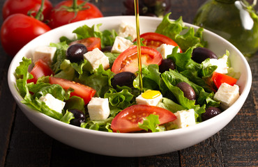 Greek Salad with Olives Tomatos and Feta Cheese on a Rustic Wood Table