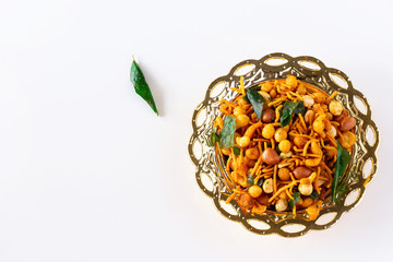 South indian spicy crunchy mix Nimco or Namkeen with peanut, rice, curry leaves and spice golden bowl background isolated top view.