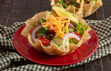 Taco Salad in a Crunch Corn Tortilla Bowl Isolated on Wooden Table