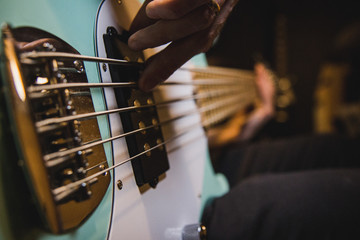Closeup on the bass guitar strings, while someone is playing