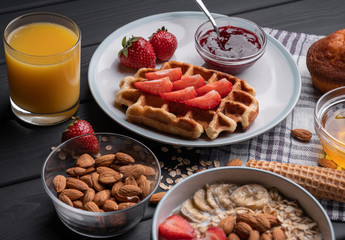Breakfast. Oatmeal. Muesli. Snack. Sweet waffles. Morning fresh food. Berry, almond, jam, juice. Dessert on black table background. Top view