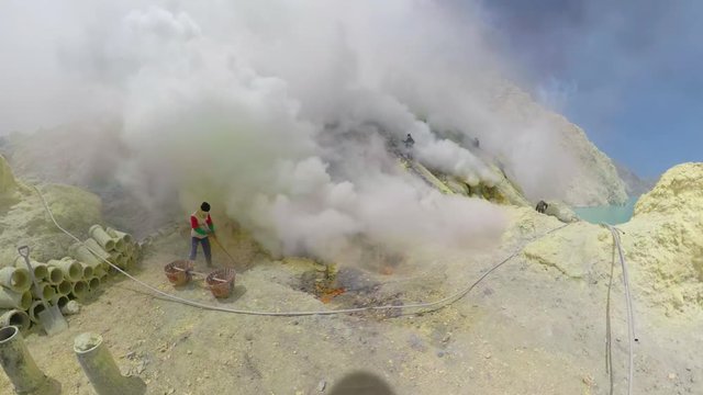 workers mine sulfur by hand, crater acid lake Kawah Ijen. mountain landscape Sulfur gas, smoke. Indonesia, Jawa
