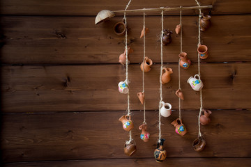 Miniature clay jugs hanging from a rope. Wooden wall decoration with Rural little clay jugs with...