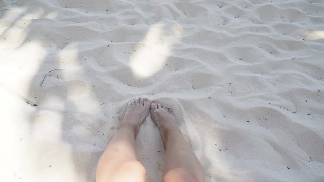 female feet on the white sand. sandy beach and palm shade. 4K