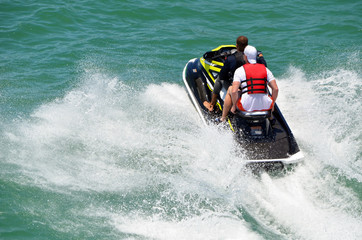 Two young men riding tandem on a speeding jetski