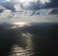 Aerial view. A calm sea with sun light beaming through the clouds.