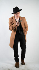 young man in a formal suit and hat with a gun in his hands on a white background in the Studio alone