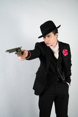 young man in a formal suit and hat with a gun in his hands on a white background in the Studio alone