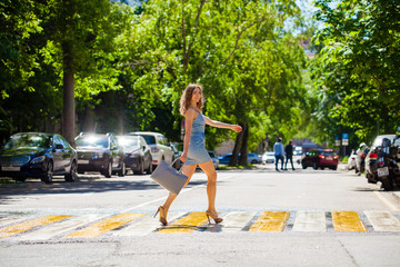 Young beautiful woman in a blue short dress walking on the road