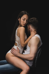 beautiful asian woman in white lingerie sitting on knees of boyfriend and looking down isolated on...