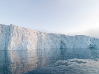 Fototapeta na wymiar The glaciers are melting on arctic ocean in Greenland. Big glaciers day by day broking and dangerous for world climate system. Shooting day was foggy weather and glaciers didn't look clear. 