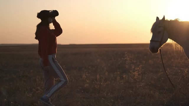 Girl in virtual reality glasses is standing in the middle of a large field