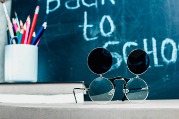 back to school. the concept of the end of the summer holidays and the beginning of the school year. chalk board and pencils and glasses.