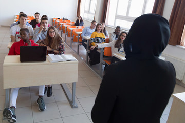 Female muslim professor explain lesson to students and interact with them in the classroom.Helping...