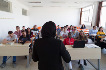 Female muslim professor explain lesson to students and interact with them in the classroom.Helping...
