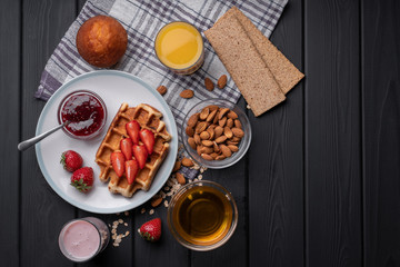 Crispy waffle with fruit for breakfast. Healthy food. Vegan dishes. Chocolate muffin and berry yogurt. On a black background