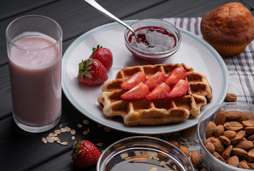Homemade waffles with berry and nuts on black table background. Sweet dessert. Delicious food