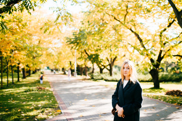 Beautiful lady walking along the alley with autumn trees