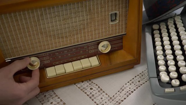 Using an old tube radio. 50's 60's 70's vintage scene. Historical reenactment concept.
