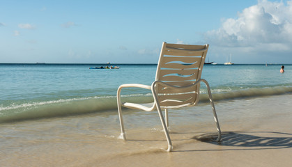 Empty white armchair at the edge of the sea