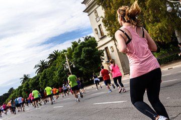 Obraz premium Pretty blond young girl running exercising in a running race surrounded by other runners.