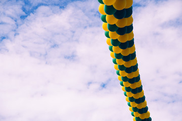 Fototapeta premium Background with copy space of many inflated balloons hanging isolated on a blue sky with clouds.