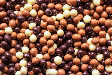 Chocolate covered nuts in different colors. close-up on the bench.. .