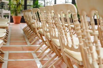Many empty white wooden chairs lined up for a retro style event.