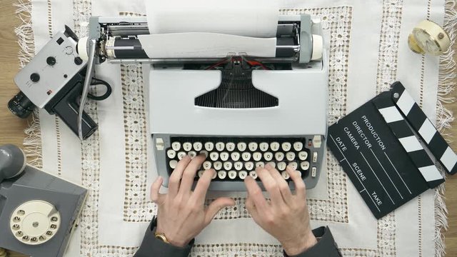 Old time filmmaker producer typing on a typewriter. 50's 60's 70's vintage scene. Historical reenactment concept.