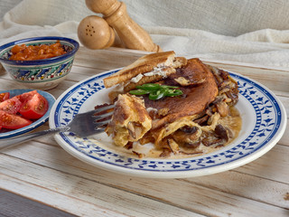 Omelet with fried onions and mushrooms.Baked beans and fresh tomatoes.On a wooden tray.