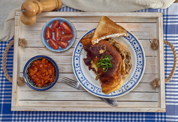 Omelet with fried onions and mushrooms.Baked beans and fresh tomatoes.On a wooden tray.