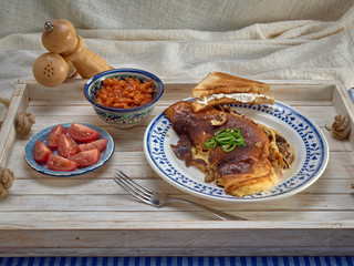 Omelet with fried onions and mushrooms.Baked beans and fresh tomatoes.On a wooden tray.