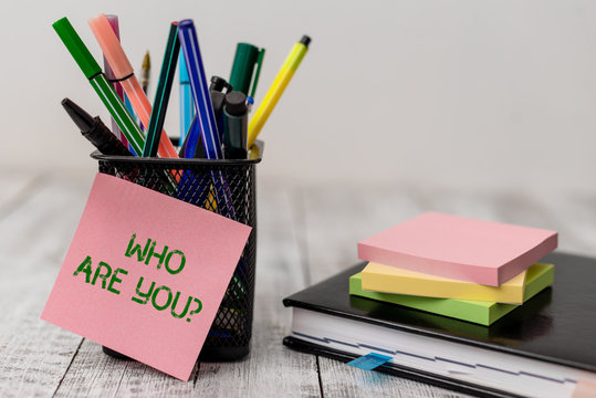 Handwriting text Who Are You question. Conceptual photo asking demonstrating identity or demonstratingal information Writing equipment and note paper sheets with agenda book on the wooden desk