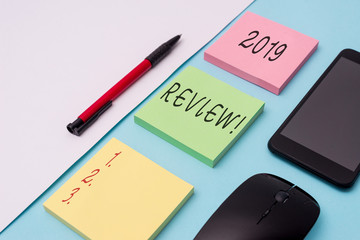 Word writing text 2019 Review. Business photo showcasing remembering past year events main actions or good shows Note papers and stationary plus gadgets placed sideways above backdrop