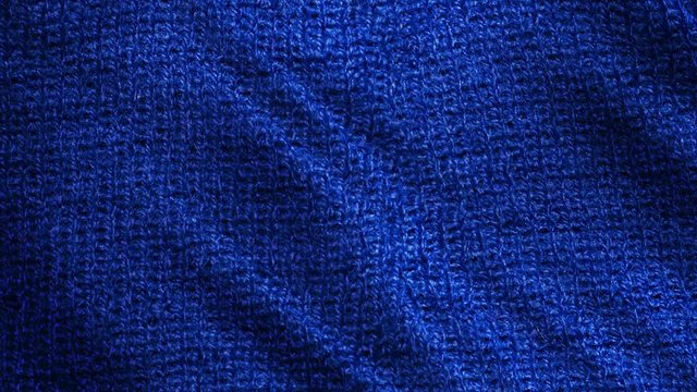 Blue knitted wool, pullover fabric is waving background. Close up, macro shot of fiber sweater