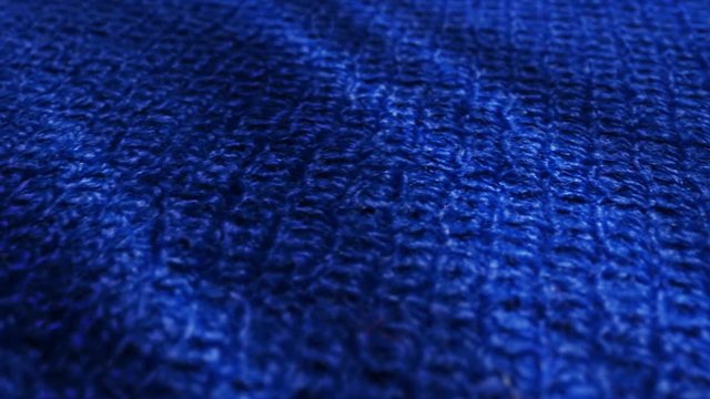 Blue knitted wool, pullover fabric is waving background. Close up, macro shot of fiber sweater
