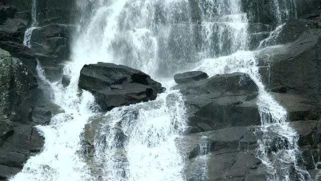 Slow-motion footage of falling water on stones at Skok Waterfall in Slovakia. Spraying torrents of water rushing down.