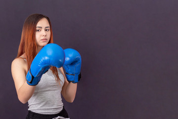 copyspace boxer girl in blue boxing gloves in a gray t-shirt in the rack background