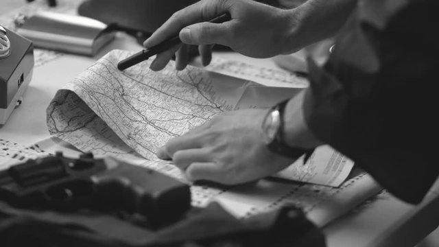 A soldier using a map to build a strategy. 50's 60's 70's vintage scene. Historical reenactment concept.