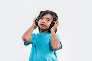 Naklejka premium Little girl listening to music on wireless headphones