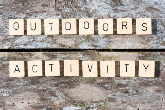 Outdoors activity words on a wood table in sunlight top view