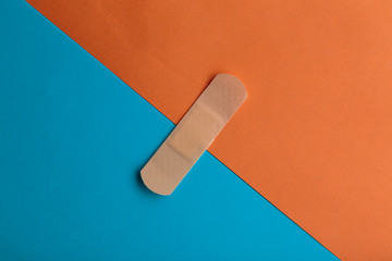 Adhesive bandage or Sticking plaster on a two colored paper background.
