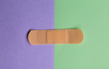 Adhesive bandage or Sticking plaster on a two colored paper background.