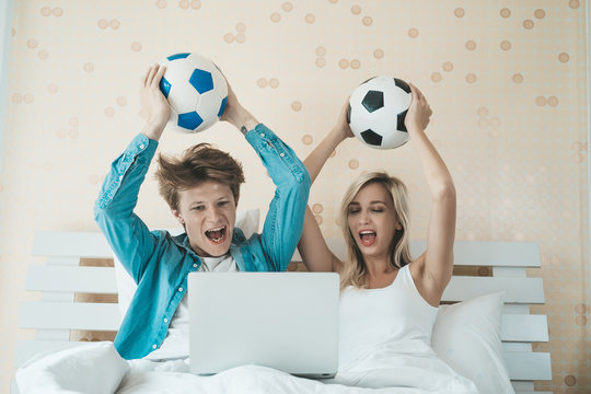 Happy couple watching soccer football on the bed
