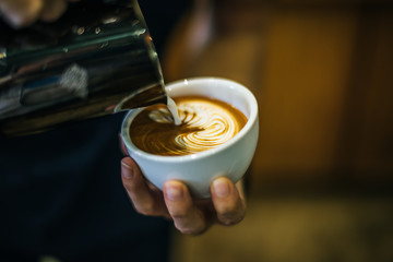 Close-up of hands barista make latte coffee art paint