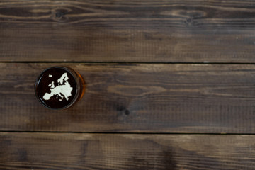Mug of dark beer with silhouettes of Europe on foam. Top view. Empty space for text